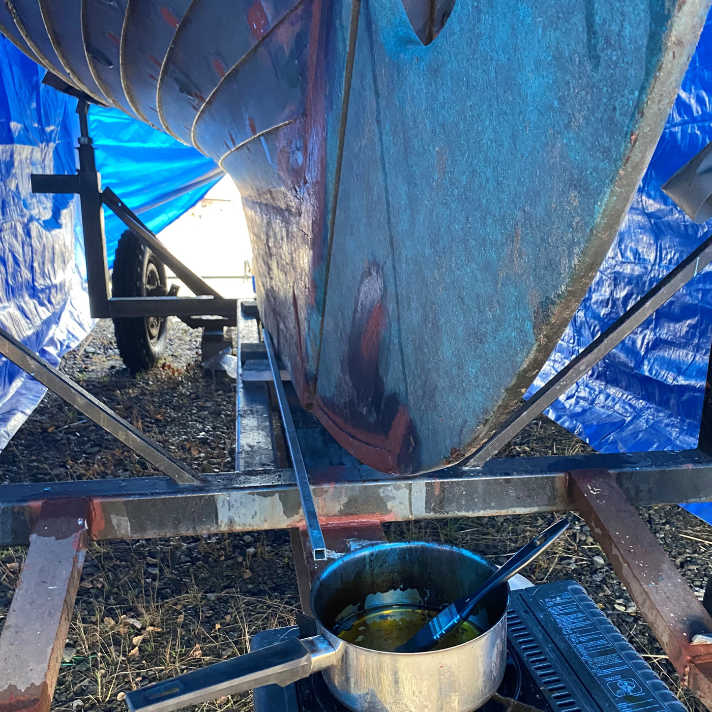 Kastrull med olja och pensel under skrovet på en båt