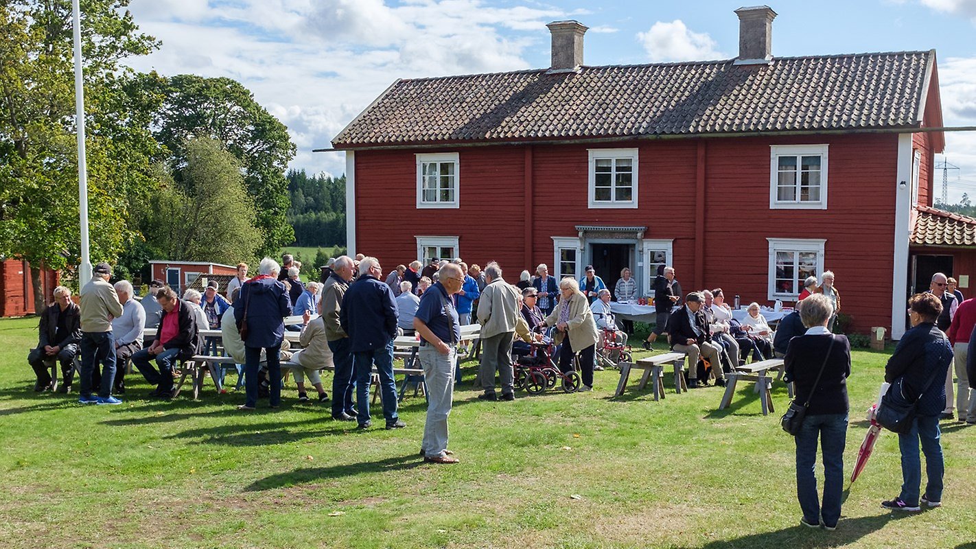 Hembygdsdag firas med flera medverkande utanför ett äldre rött trähus i Lerbäck.