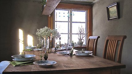 Ett dukat bord med vita blommor och tända ljus. 