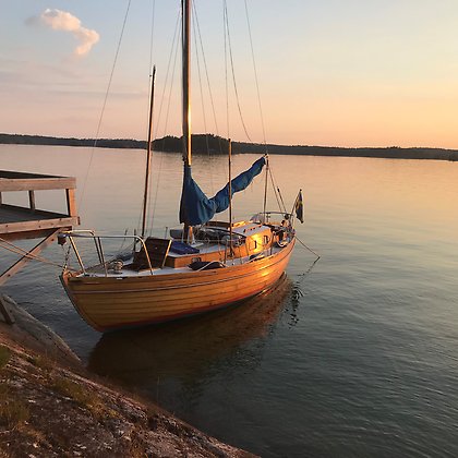 Segelbåt vid en ö i solnedgång