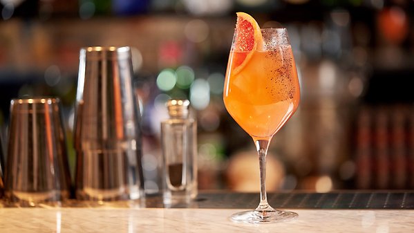 En orange drink som står på en bardisk.
