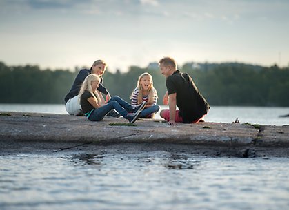 Familj sitter på en klippa ute i vattnet.