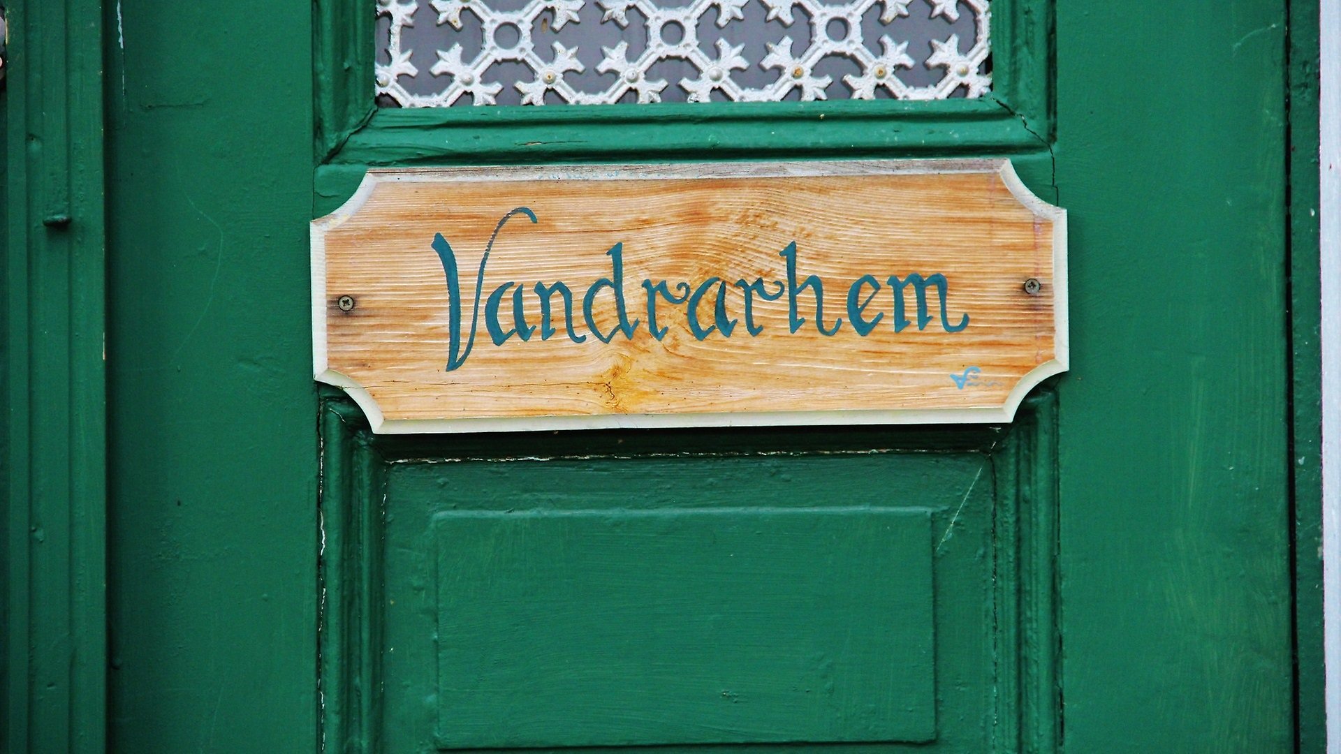 En grön dörr med en skylt där det står vandrarhem i grönt.