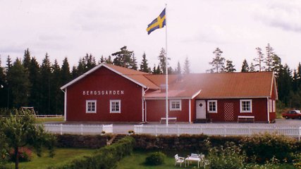 Byggnaden Bergsgården med flaggstång och svensk flagg i förgrunden.