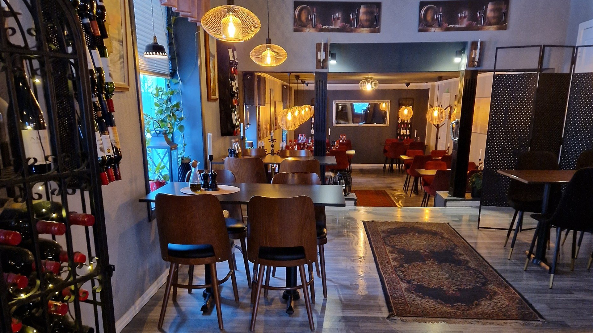 Interiör på restaurangen Casa Mia. Vinställ till vänster i bilden. bord och stolar, matta på golvet, varm belysning i taket.