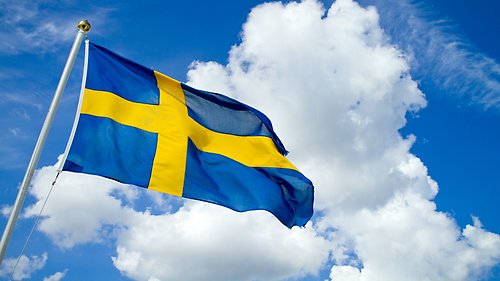 Sveriges flagga mot blå himmel och moln