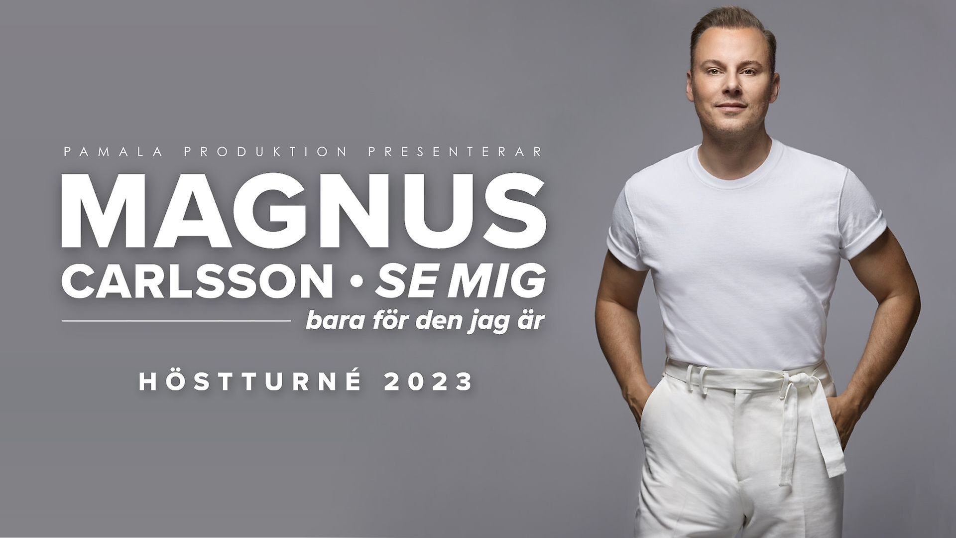 Magnus Carlsson i vita kläder framför en grå bakgrund.